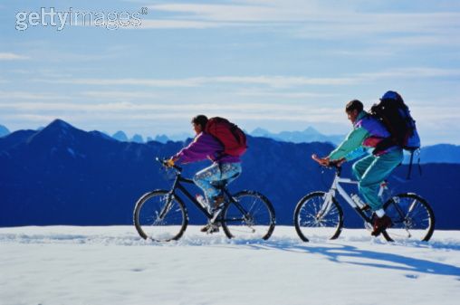 Couple with backpacks riding mountain bikes through snow.jpg